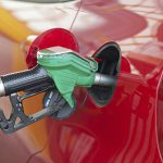 Red car at gas station being filled with fuel