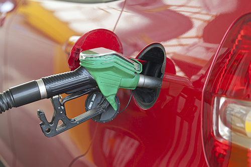 Red car at gas station being filled with fuel